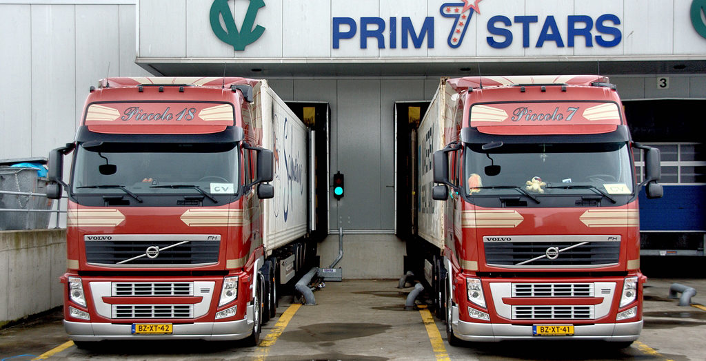 twee vrachtwagens Transport Van der Veld vrachtwagens bij een laaddock